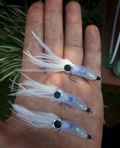 three different sized fishing lures in the palm of someone's hand, one is blue and white