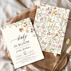 two baby in bloom cards sitting on top of a wooden plate next to dried flowers