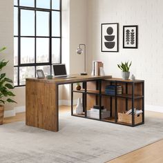 a wooden desk sitting in front of a window next to a potted plant on top of a rug