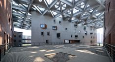 an empty courtyard with lots of windows on the ceiling and wooden walkways leading up to it