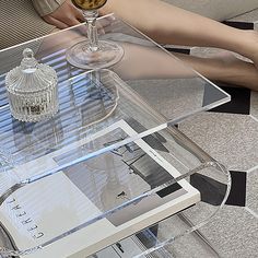 a person sitting at a glass table with a wine glass on it and a book in front of them