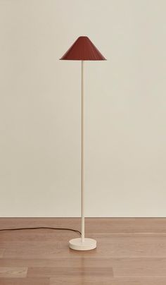 a lamp that is on top of a wooden floor in front of a white wall