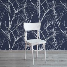 a white chair sitting in front of a wall with trees on it