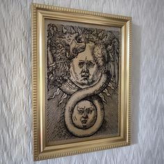 a painting hanging on the wall in front of a white wall with a gold frame