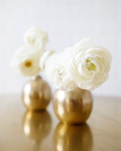 three gold vases with white flowers in them