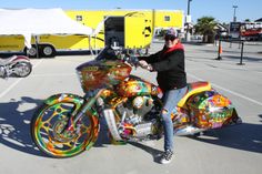 a person sitting on a colorful motorcycle in a parking lot