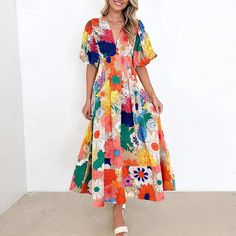 a woman standing in front of a white wall wearing a colorful dress