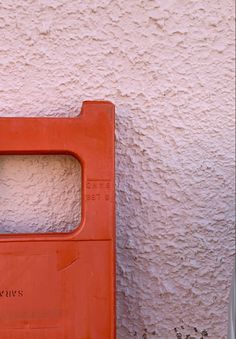 an orange box sitting on the side of a building with a cat in it's window