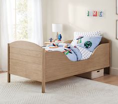 a child's bed in a bedroom with white walls and wooden floors, along with a rug on the floor