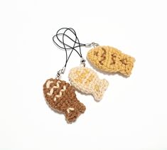 three crocheted pieces of food hanging from a cord on a white surface,