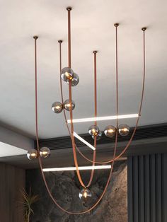 a modern chandelier hanging from the ceiling in a living room with stone walls