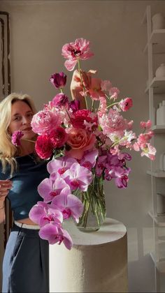 a woman standing next to a vase with flowers in it