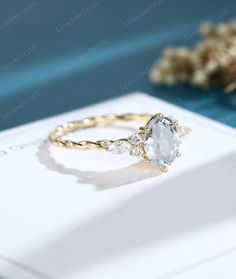 an oval shaped white diamond ring with three diamonds on the side, sitting on top of a card