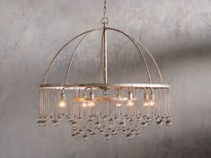 a chandelier hanging from the ceiling in a room with concrete walls and flooring