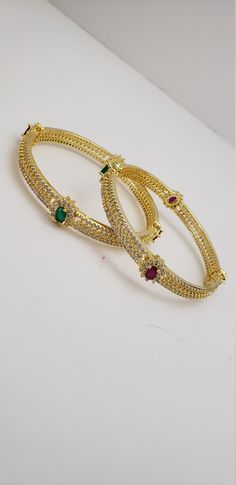 "* Handcrafted Gold Plated Bangle Set * High Quality 22 K Gold Plated 2 pc bangle set; *Bangles Sizes : 2.4 ( 2.30\" diameter of the inner circle) ; 2.6 ( 2.44\" diameter of the inner circle); * Sold as a set of 2 bangles Gorgeous gold-plated bangle/ bracelet best exemplifies the careful craftsmanship done on it -- a specialty at Nemali Jewelry. It has special tone of elegance attached to it. The intricate handmade design of the bangle / bracelet set gives it a fresh and original look. Look your Jeweled Round Bangle For Wedding, Green Hoop Jewelry For Wedding, Green Hoop Jewelry For Weddings, Hoop Bangle For Wedding, Stone Work Bangle Jewelry For Marriage, Bangle With Stone Work For Marriage, Heavy Green Bangle For Wedding, Green Wedding Bangle With Intricate Design, Emerald Bangles