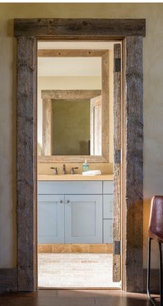 an open door leading to a bathroom with a sink and mirror on the wall next to a chair