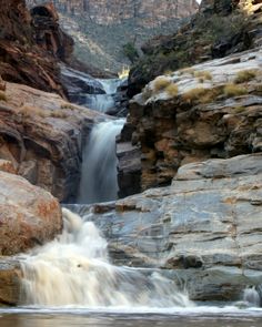 there is a waterfall in the middle of some rocks and water flowing down it's sides