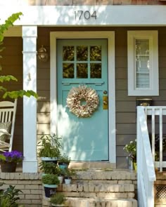 a blue front door with a wreath hanging on it's side and steps leading up to the house