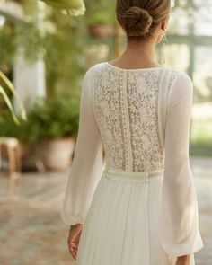 the back of a woman's wedding dress, with long sleeves and lace detailing