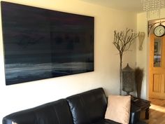 a living room with a black leather couch and clock on the wall next to it