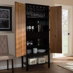 a cabinet with wine glasses and cups on it next to a chair in a living room