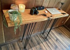 a wooden table topped with a laptop computer next to a potted plant and candle