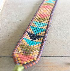 a colorful beaded object sitting on top of a wooden floor next to a wall