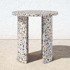 a small white table sitting on top of a cement floor next to a wall and window