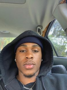 a man sitting in the back seat of a car wearing a hoodie and looking at the camera