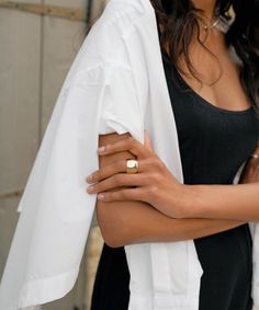 a woman wearing a gold ring with a white jacket over her shoulders and black dress