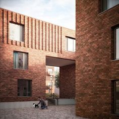 two people sitting on the ground in front of some brick buildings with windows and doors