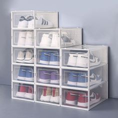 several clear bins filled with various pairs of shoes on top of each other in front of a gray wall