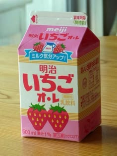 a carton of strawberry milk sitting on top of a wooden table