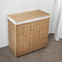 a wicker laundry basket sitting next to a white shower curtain