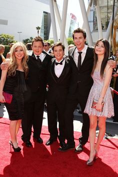 a group of people standing on top of a red carpet next to each other at an event