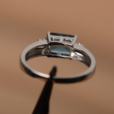 It is a London blue topaz ring. The main stone is 6mm*8mm emerald cut, weight about 2.0 carats. The basic metal is sterling silver and plated with rhodium. To change the metal to a solid gold (white/rose) or platinum is also available, please ask for a quotation if you want. You can also go to my shop Home for more elegant rings: https://www.etsy.com/shop/godjewelry?ref=hdr_shop_menu More topaz rings: https://www.etsy.com/shop/godjewelry?ref=hdr_shop_menu§ion_id=20715039 Customization is always Silver Solitaire Engagement Ring, Pink Gemstones Ring, Topaz Rings, August Birthstone Ring, Blue Gemstone Ring, Elegant Rings, Pink Engagement Ring, Green Sapphire Ring, Gold Anniversary Rings