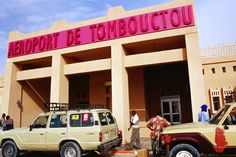 two vehicles parked in front of a building with people standing around it and the words aeroport de toboucctou on top