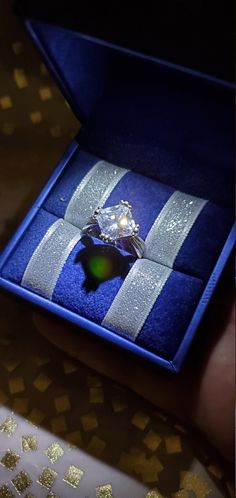 someone is holding an engagement ring in a blue box