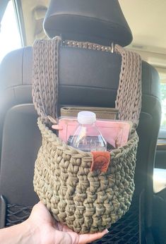 a hand holding a basket with bottles in it on the back seat of a car