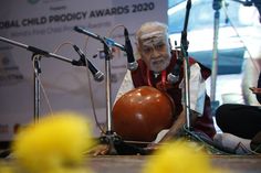 an old man sitting in front of microphones with a ball on the ground next to him