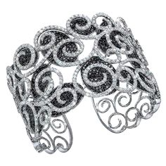 Black and white diamond pavé open-scroll motif cuff bracelet. Set in 18-karat white gold, the white diamonds are set in a scroll pattern which overlay the black diamond ovals. The cuff is 1.75" at the widest and tapers down slightly towards the back. One side of the bracelet is hinged for easy on and off. Inside measurement is 2 1/8' across. 839 Black diamonds = 12.00 carats 527 white diamonds =9.12 carats Black Diamond Bracelets, Black Diamond Bracelet, Diamond Cuff Bracelet, Diamond Bangles, Buying Gold, Diamond Jewelry Designs, Designer Jewellery, Diamond Bracelets, Beautiful Bracelet