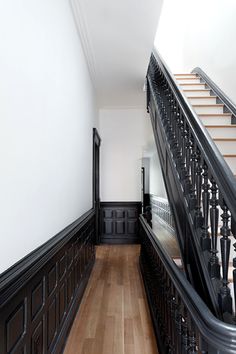 an empty hallway with wooden floors and black railings on either side of the stairs