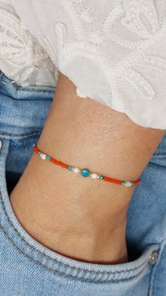 a woman wearing a bracelet with beads on it's wrist and an orange cord