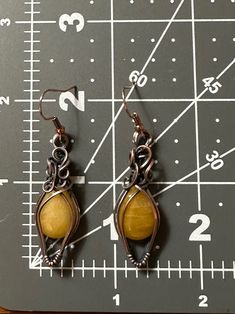 Gorgeous yellow earrings wrapped in swirly oxidized copper wire. Earrings are 2.25 inches long and .5 inches wide. Comes with nickel free french wire hooks. Hand Forged Bronze Earrings With Copper Wire, Hand Forged Copper Wire Drop Earrings, Handmade Yellow Copper Jewelry, Handmade Brown Copper Wire Earrings, Brown Adjustable Copper Wire Earrings, Artisan Hand Wrapped Copper Earrings, Copper Wire Wrapped Brown Earrings, Wire Wrapped Brown Copper Earrings, Brown Copper Wire Wrapped Earrings