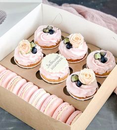 a box filled with pink cupcakes covered in frosting and topped with flowers