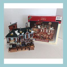 a box with a model of a house in front of it and a toy train set next to it