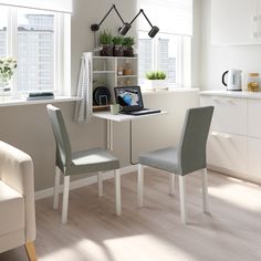 two chairs sit at a small table in front of a window with open shelving