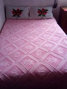 a pink crocheted bedspread with poinsettis on the pillow