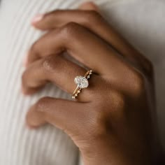 a woman's hand wearing a gold ring with a diamond on the middle finger