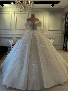 a white ball gown with silver sequins on the skirt and off - shoulder